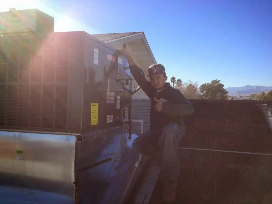 HVAC technician performing AC Tune-Up on a rooftop unit in Davenport